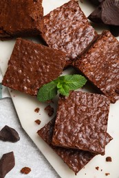 Delicious chocolate brownies with fresh mint on grey table, flat lay