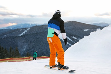 Photo of Man snowboarding on hill in mountains. Winter vacation