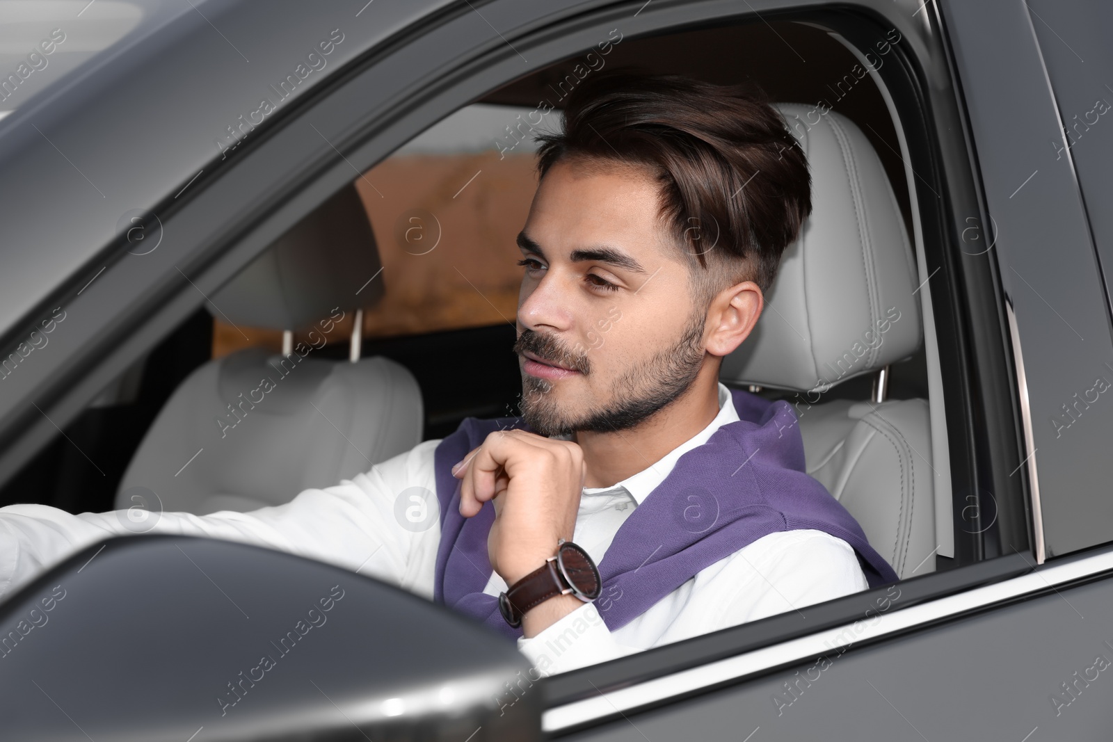 Photo of Young handsome man in driver's seat of modern car