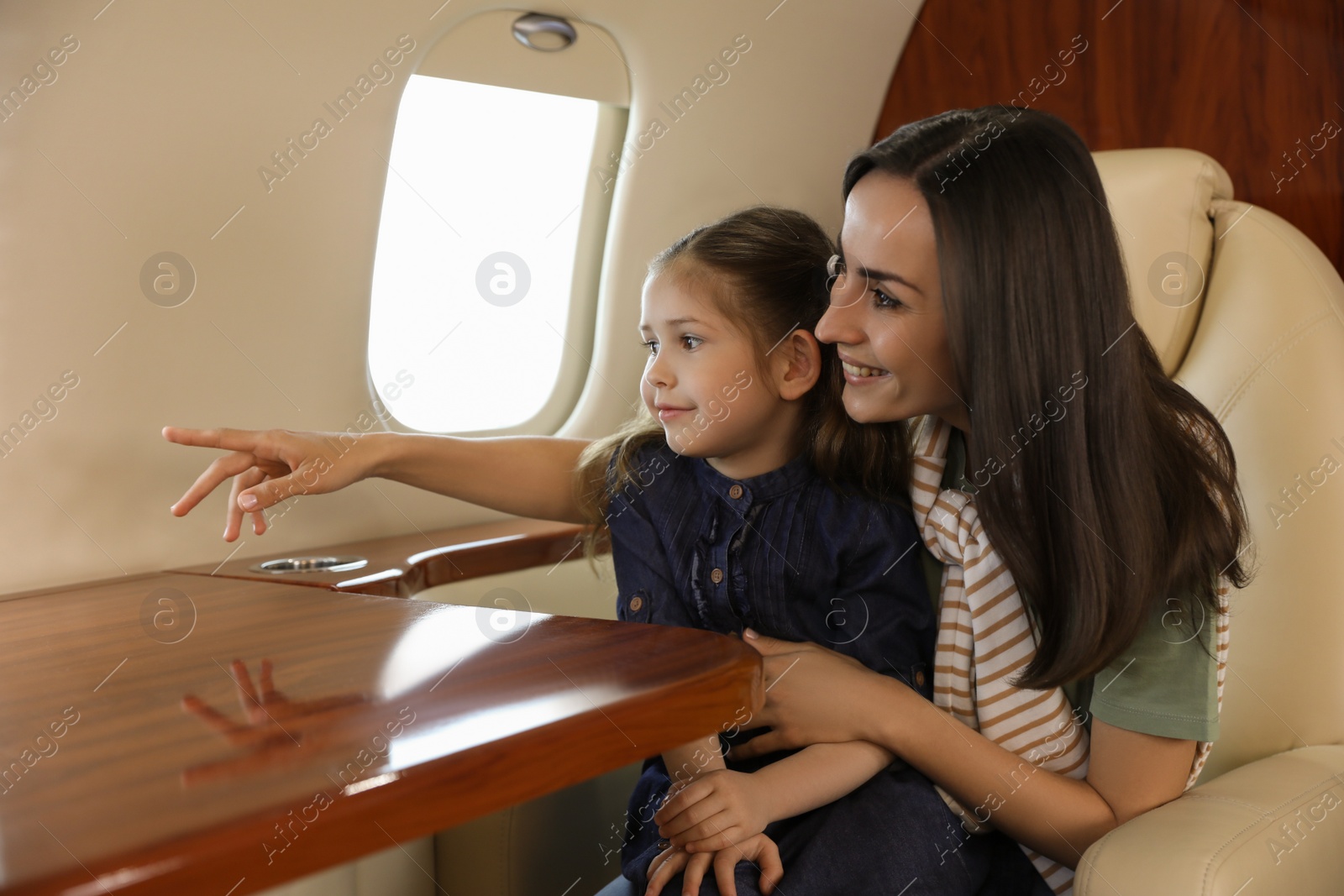 Photo of Mother with daughter looking out window in airplane during flight