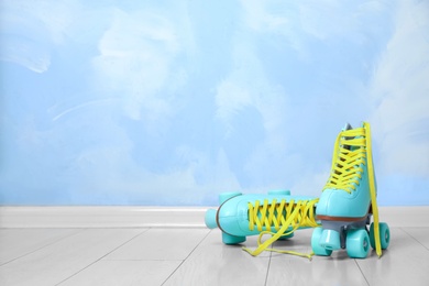 Vintage roller skates on floor near color wall. Space for text