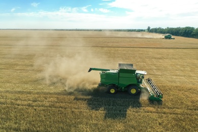 Photo of Modern combine harvester working in field on sunny day. Agriculture industry