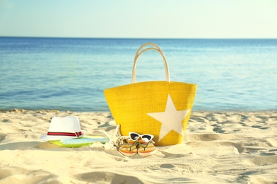 Composition with stylish beach accessories on sand near sea