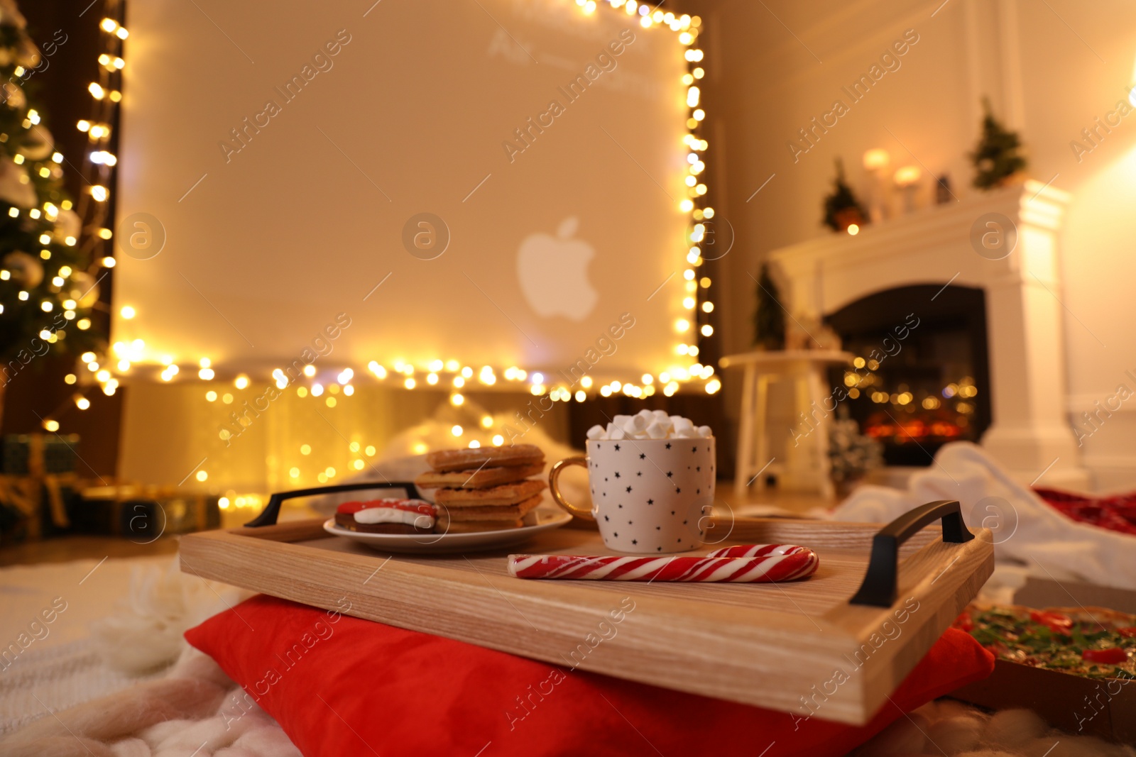 Photo of MYKOLAIV, UKRAINE - DECEMBER 24, 2020: Video projector screen displaying Apple company logo in room, focus on tray with snack and drink