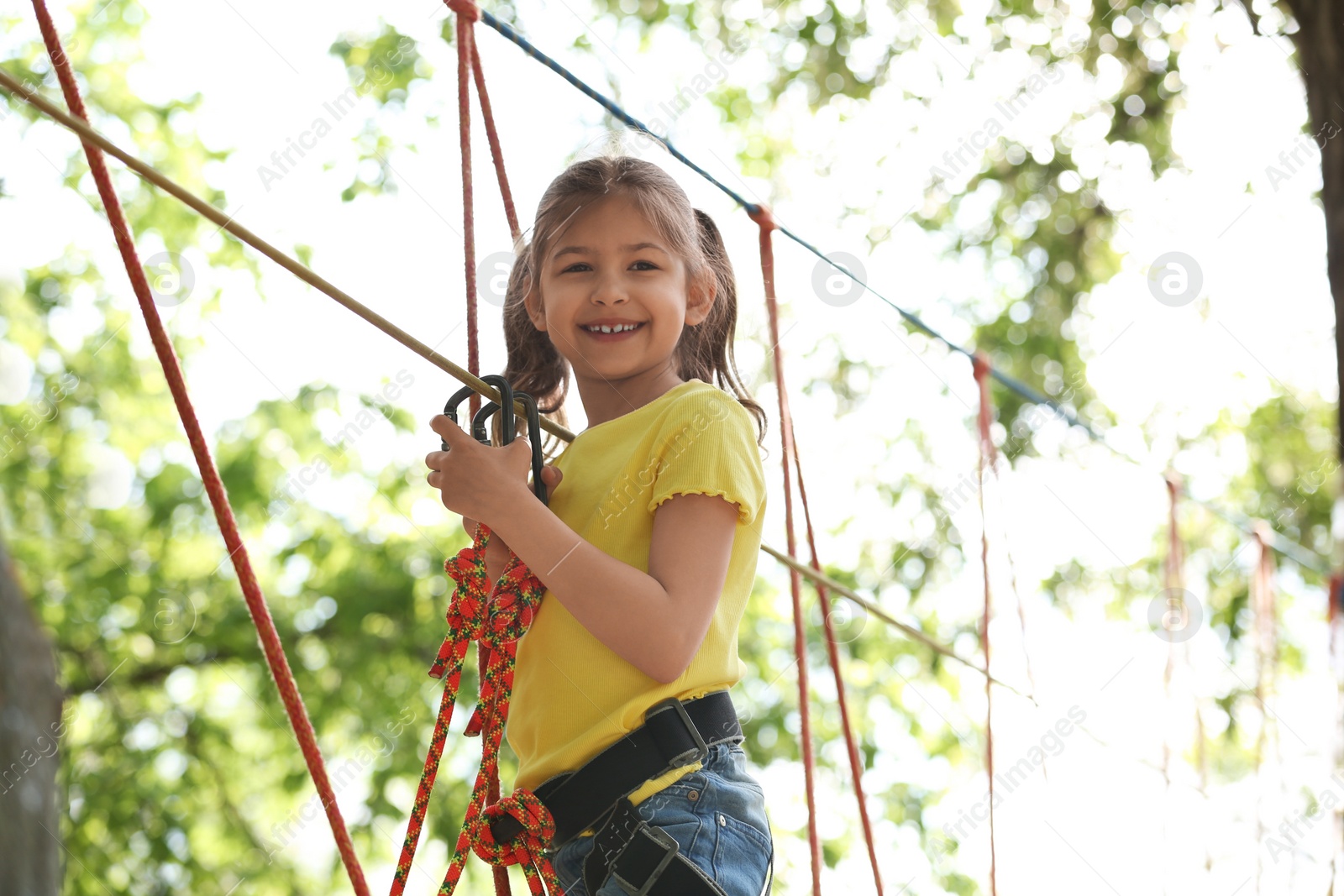 Photo of Little girl climbing in adventure park. Summer camp