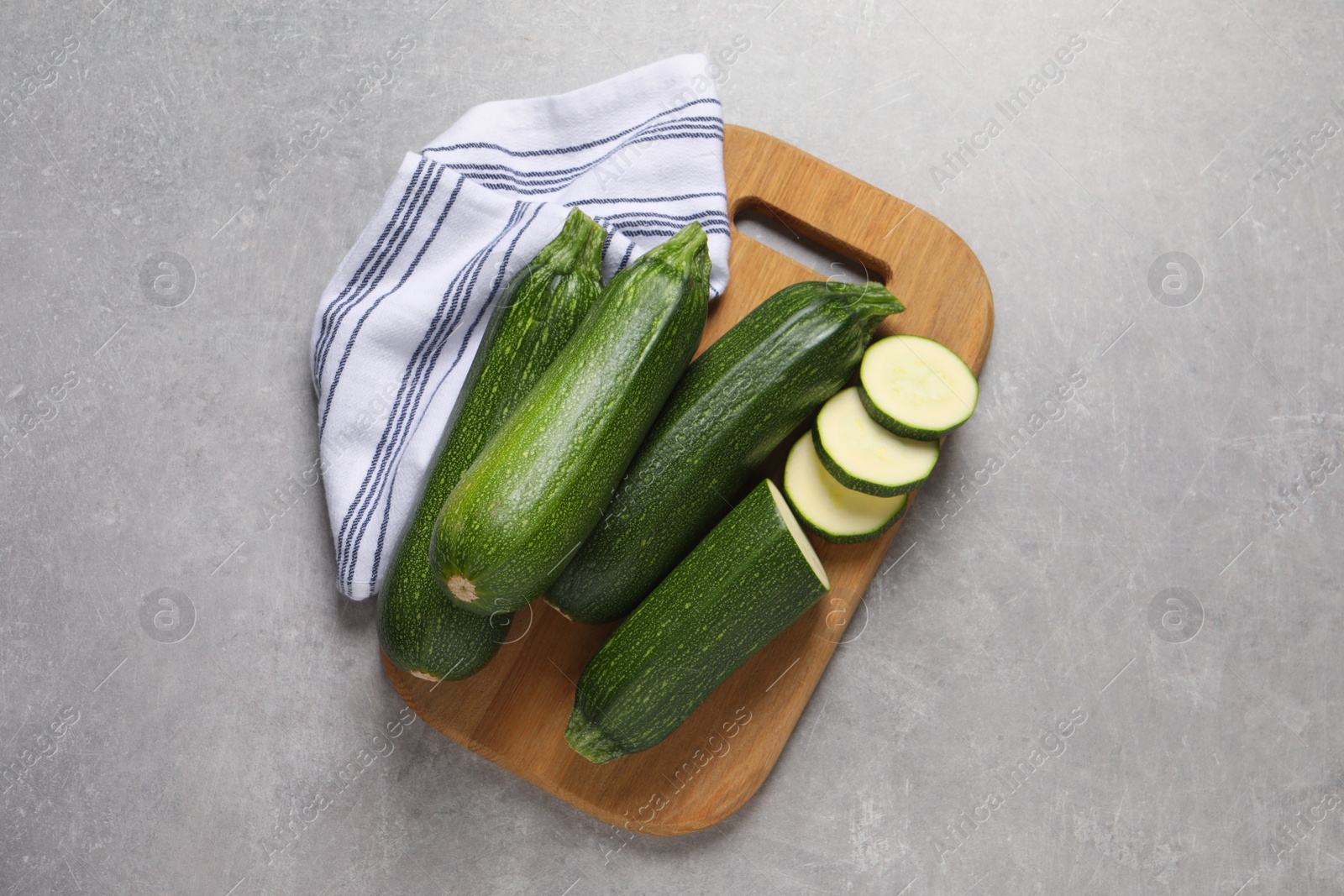 Photo of Whole and cut ripe zucchinis on light grey table, top view