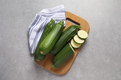 Photo of Whole and cut ripe zucchinis on light grey table, top view