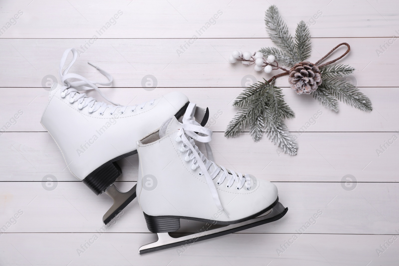 Photo of Pair of ice skates and Christmas decor on white wooden background, flat lay