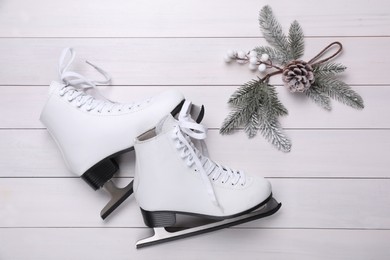 Pair of ice skates and Christmas decor on white wooden background, flat lay