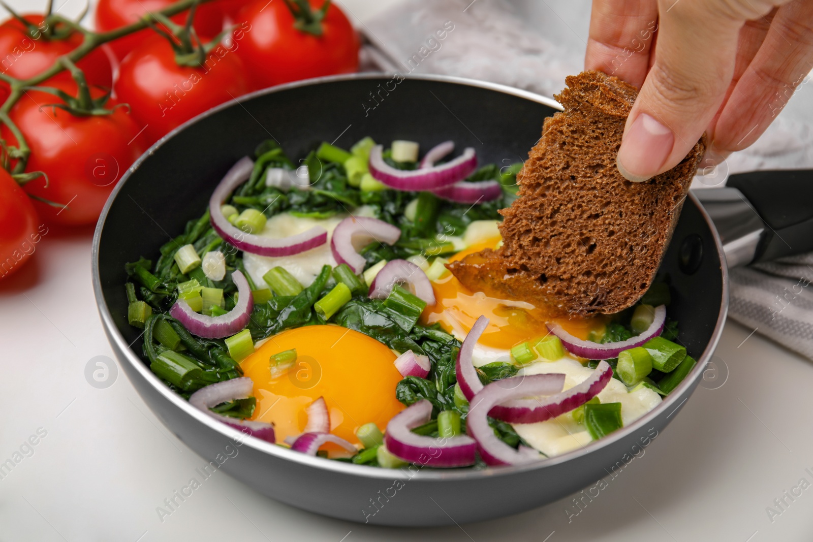 Photo of Woman dipping piece of bread into egg yolk, closeup. Eating tasty Shakshuka