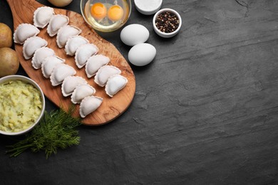 Raw dumplings (varenyky) and ingredients on black table, flat lay. Space for text