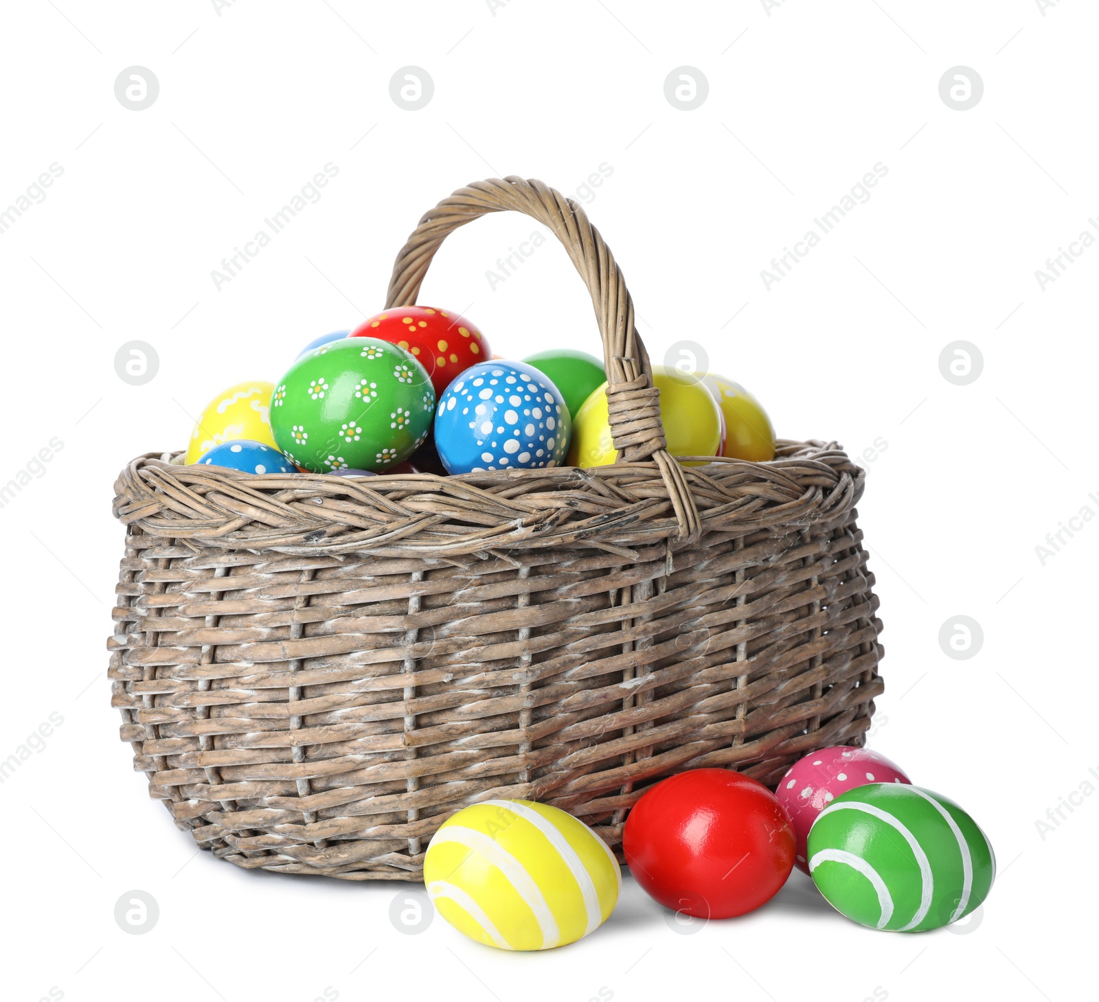 Photo of Decorated Easter eggs in wicker basket on white background