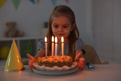 Photo of Cute girl with birthday cake at table indoors