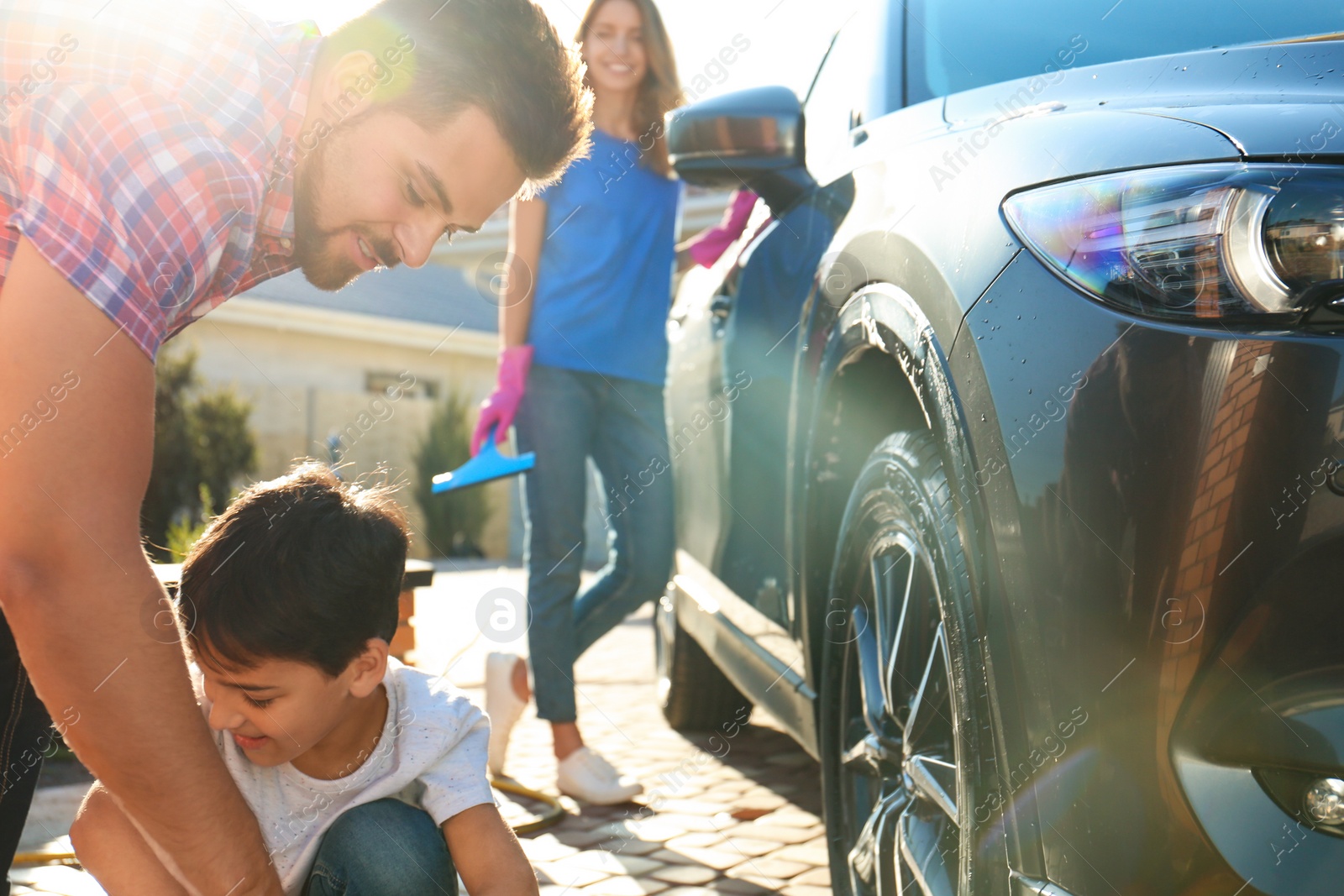 Photo of Happy family washing car at backyard on sunny day