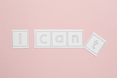 Motivation concept. Changing phrase from I Can't into I Can by removing paper with letter T on pink background, top view