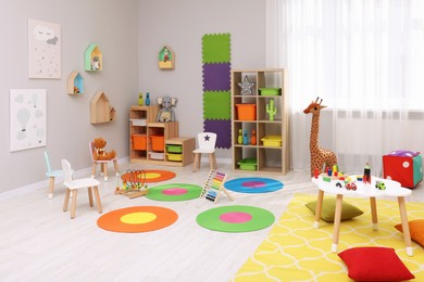 Child`s playroom with different toys and furniture. Cozy kindergarten interior