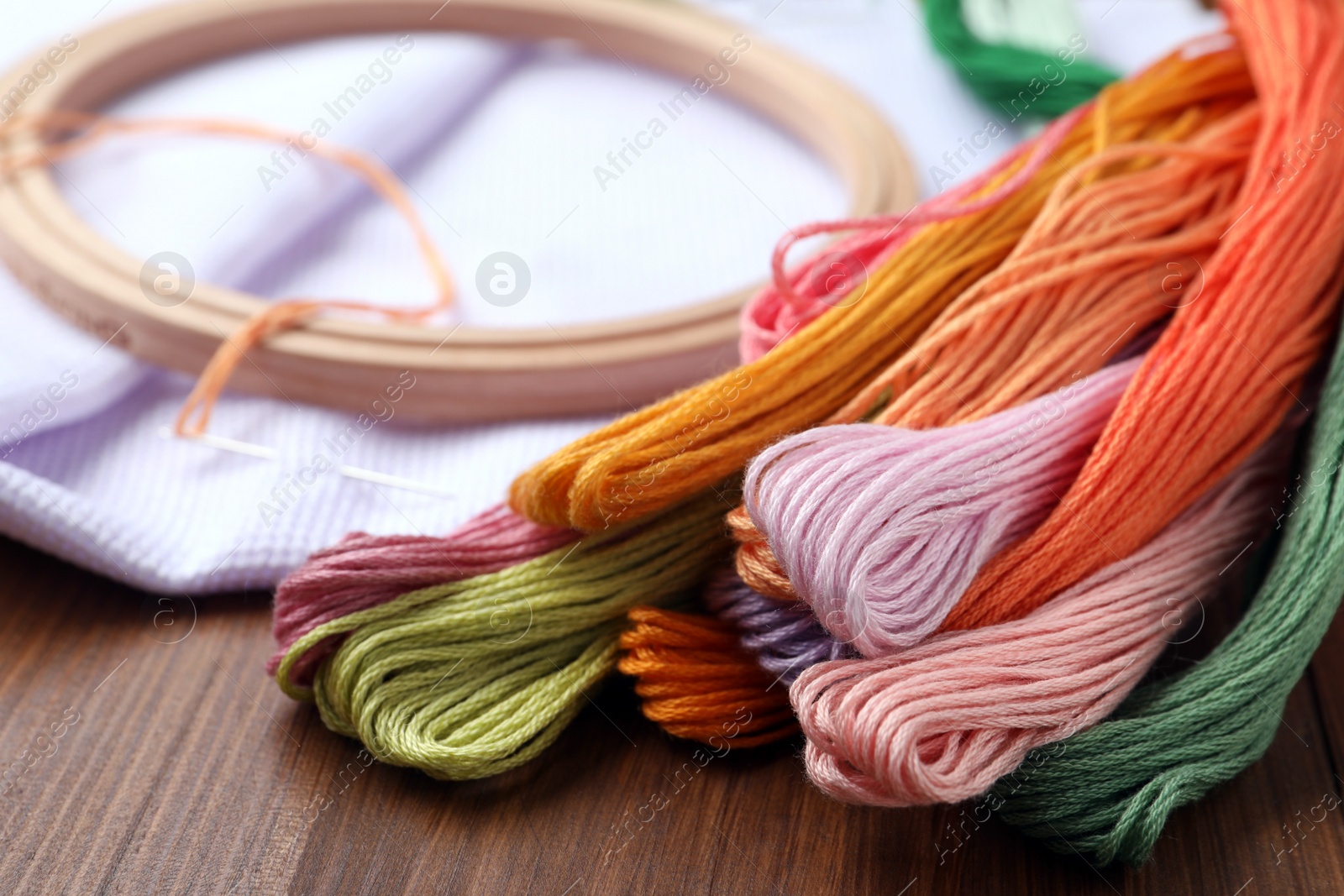 Photo of Colorful embroidery floss set on wooden table, closeup