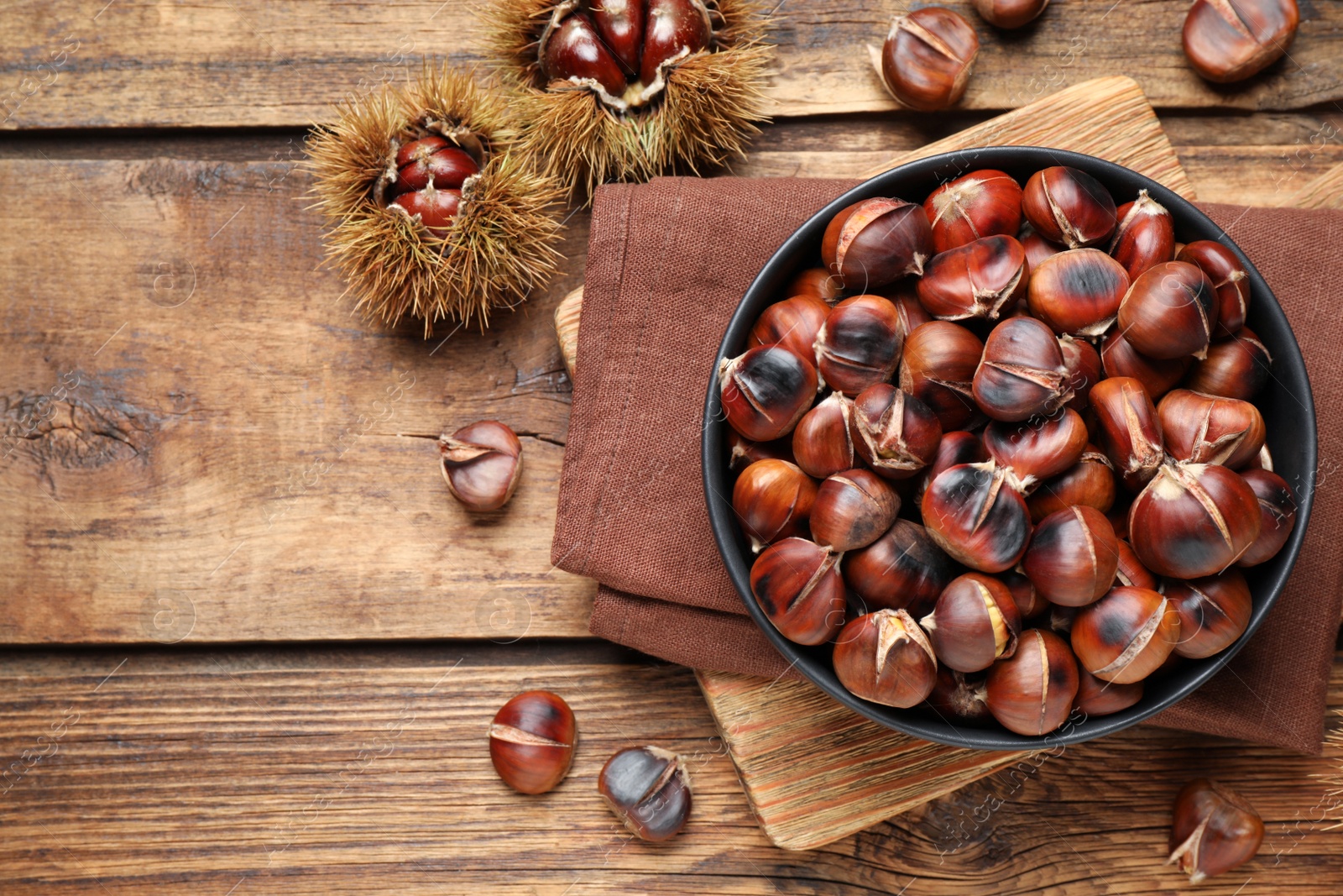 Photo of Delicious roasted edible chestnuts on wooden table, flat lay