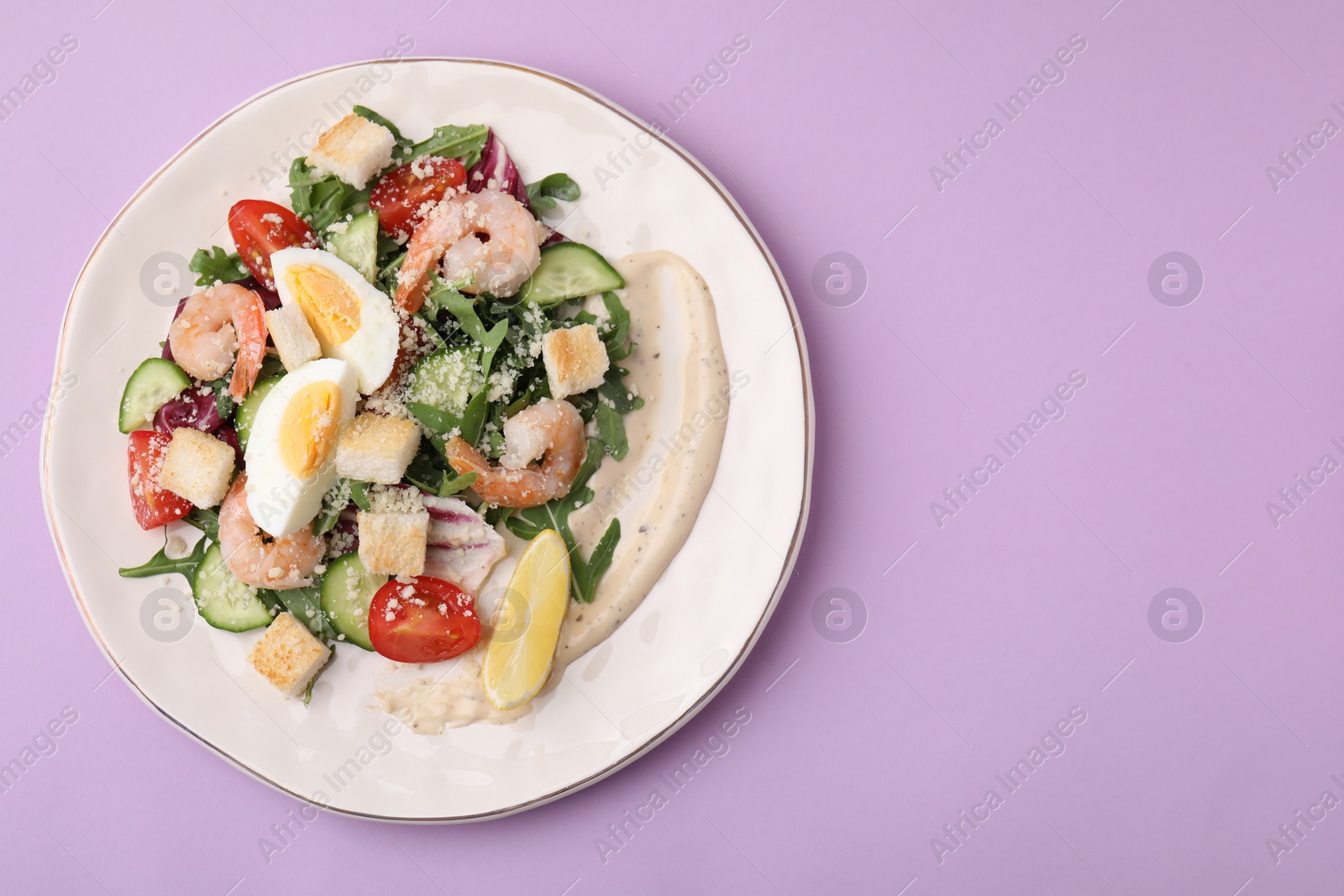 Photo of Delicious Caesar salad with shrimps on violet background, top view. Space for text