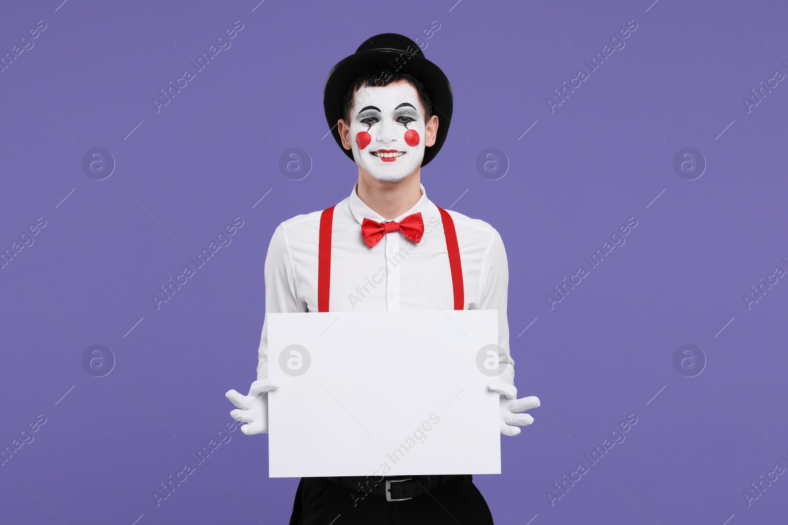 Photo of Funny mime artist with blank sign on purple background