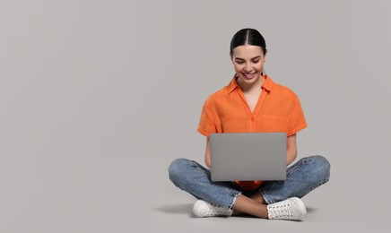 Photo of Happy woman using laptop on light gray background