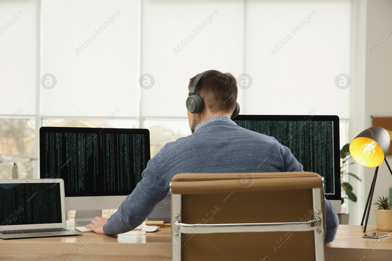 Photo of Programmer with headphones working at desk in office