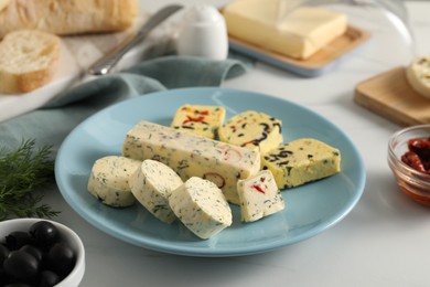 Photo of Different types of tasty butter, dill, olives and bread on white table