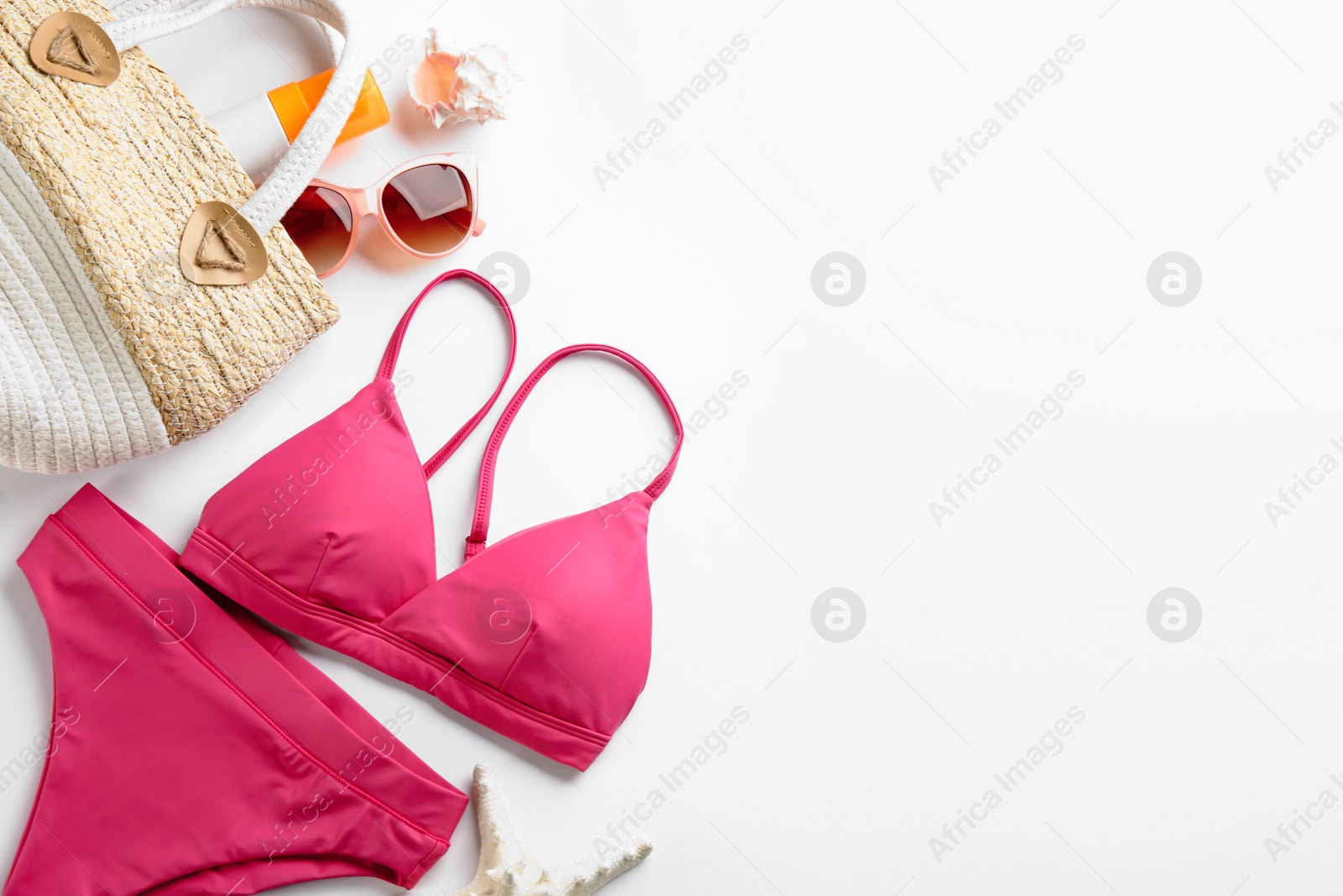 Photo of Beautiful pink bikini and beach accessories on white background, flat lay. Space for text