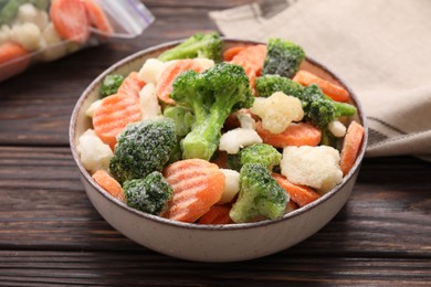 Mix of different frozen vegetables in bowl on wooden table, closeup