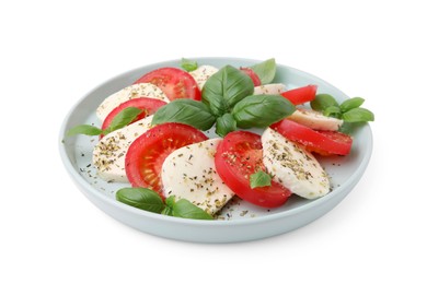 Photo of Plate of delicious Caprese salad with tomatoes, mozzarella, basil and spices isolated on white