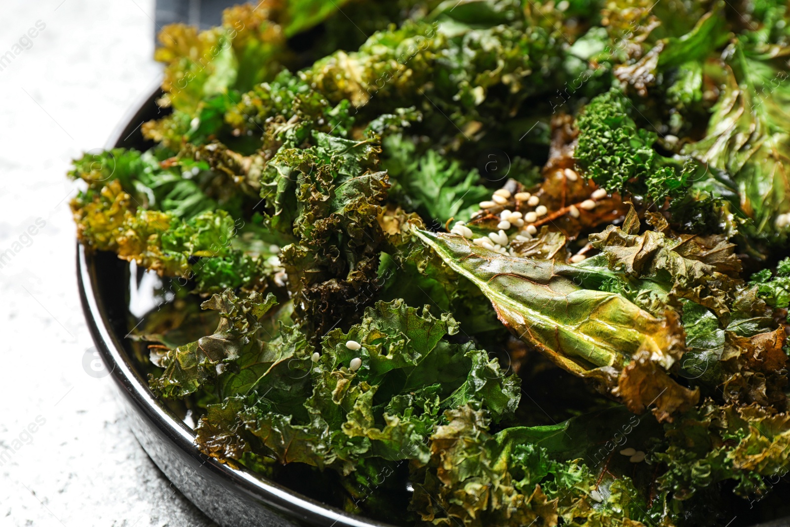 Photo of Tasty baked kale chips on table, closeup