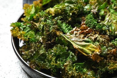 Tasty baked kale chips on table, closeup