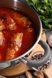 Photo of Delicious stuffed cabbage rolls cooked with homemade tomato sauce in pot on table, closeup