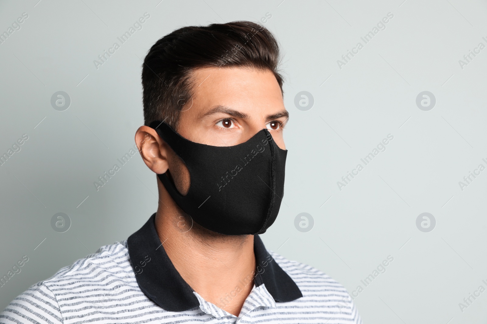 Photo of Man in protective face mask on light grey background