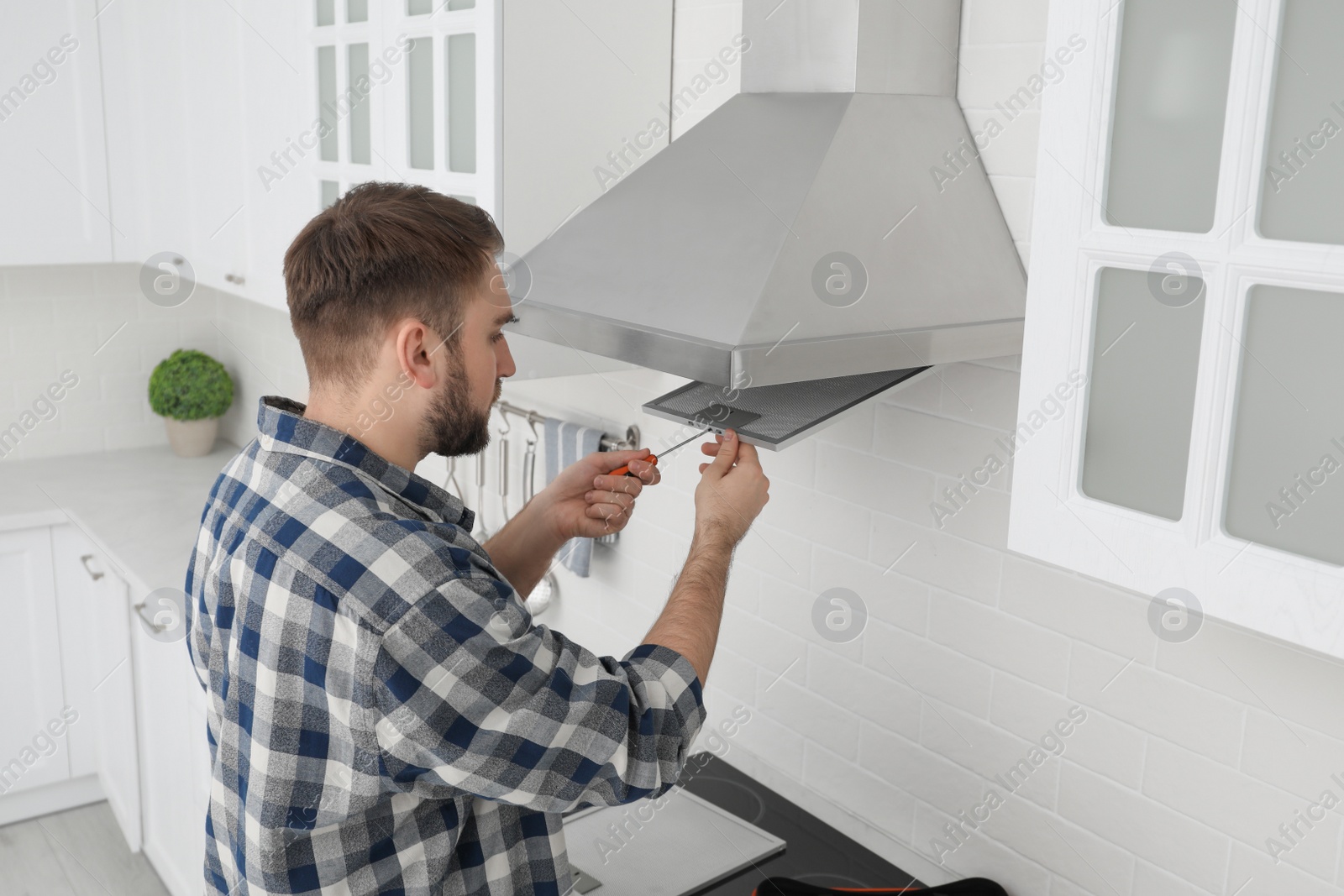 Photo of Man repairing modern cooker hood in kitchen