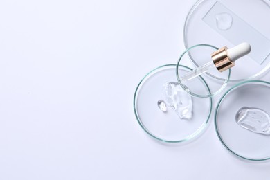 Photo of Petri dishes with samples of cosmetic serums and pipette on white background, flat lay. Space for text