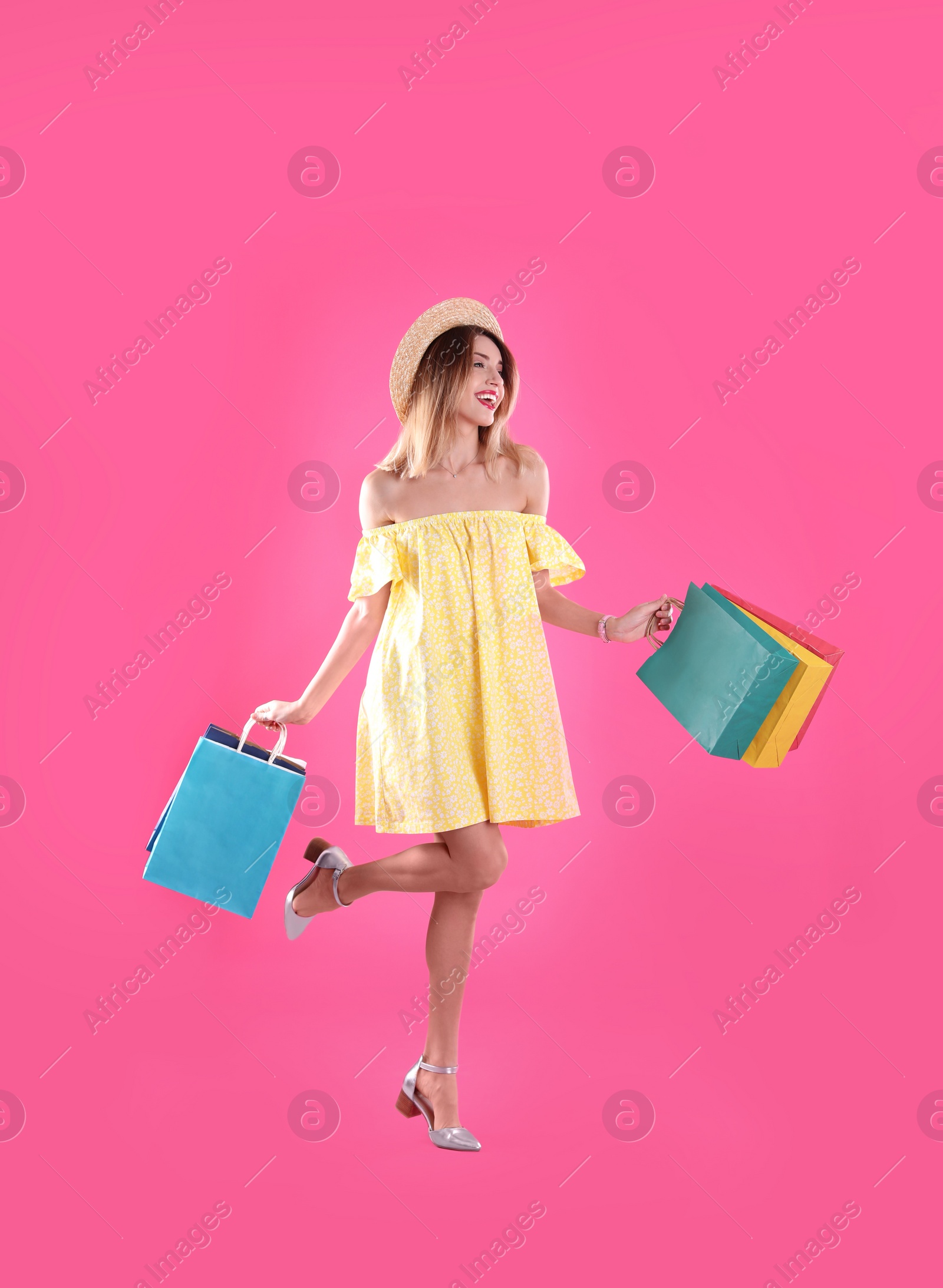 Photo of Beautiful young woman with shopping bags on color background