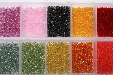 Photo of Plastic organizers with different beads as background, top view