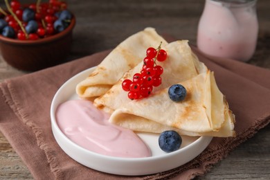 Delicious crepes with natural yogurt, blueberries and red currants on wooden table