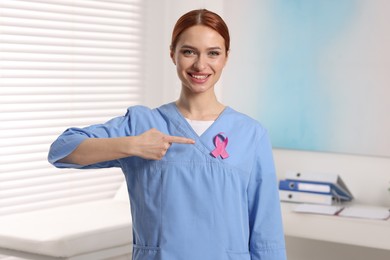 Photo of Mammologist pointing at pink ribbon in hospital. Breast cancer awareness