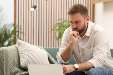 Young man working with laptop at home, space for text