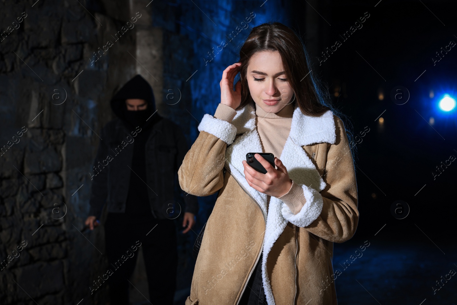 Photo of Man with knife stalking young woman in alley at night