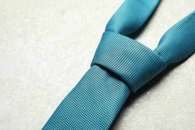 Photo of One blue necktie on light textured table, above view. Space for text