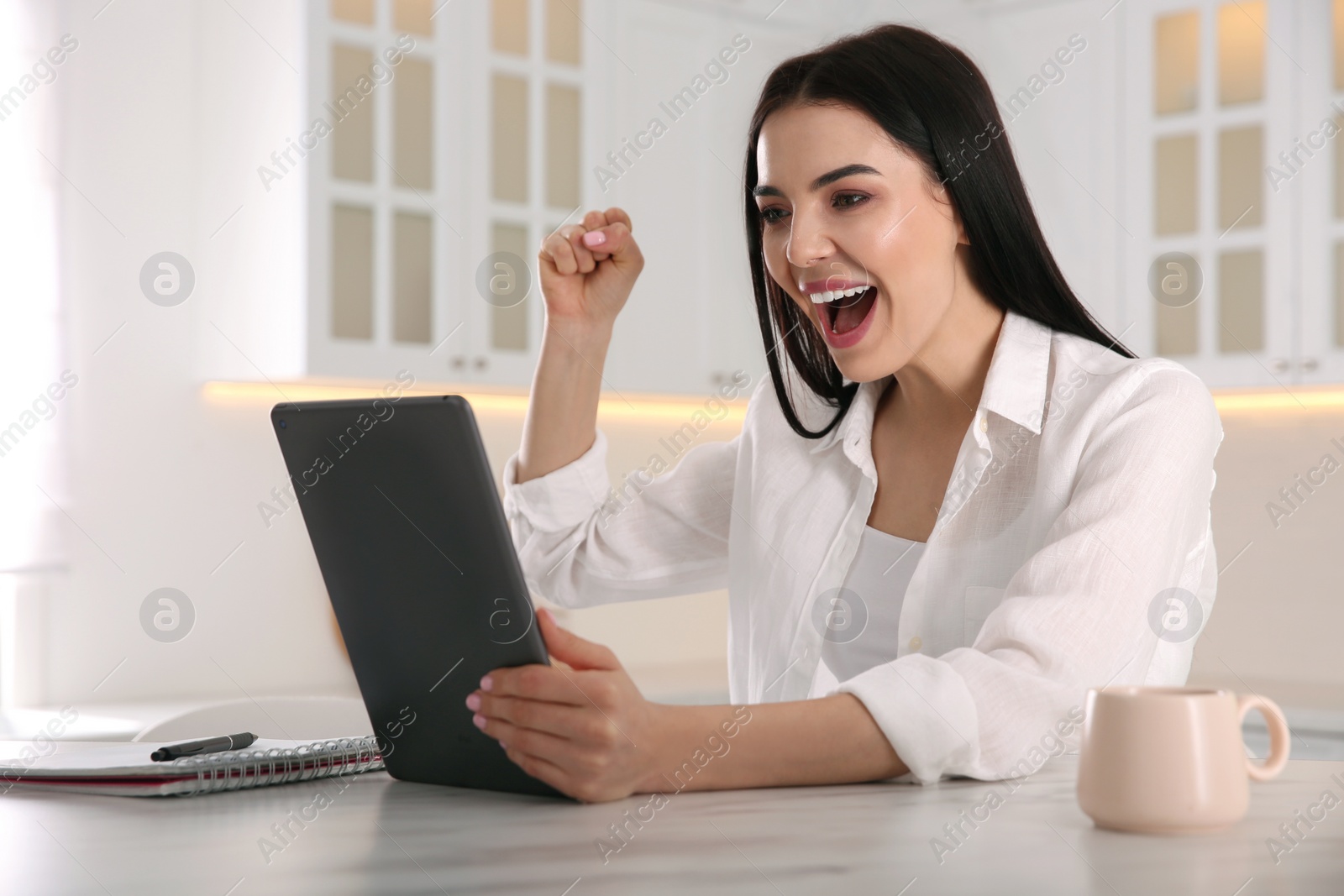 Photo of Emotional woman participating in online auction using tablet at home