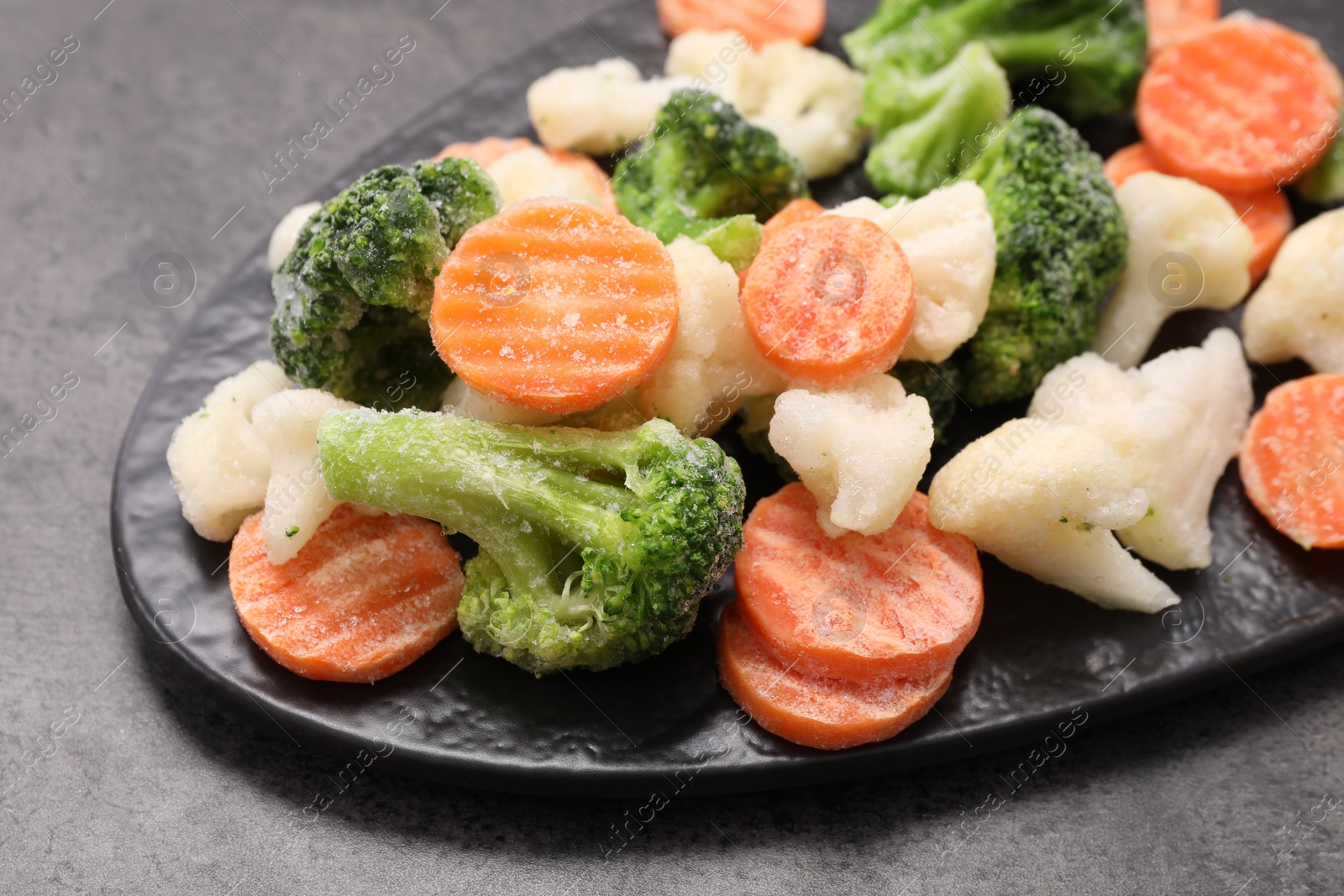 Photo of Mix of different frozen vegetables on grey table, closeup