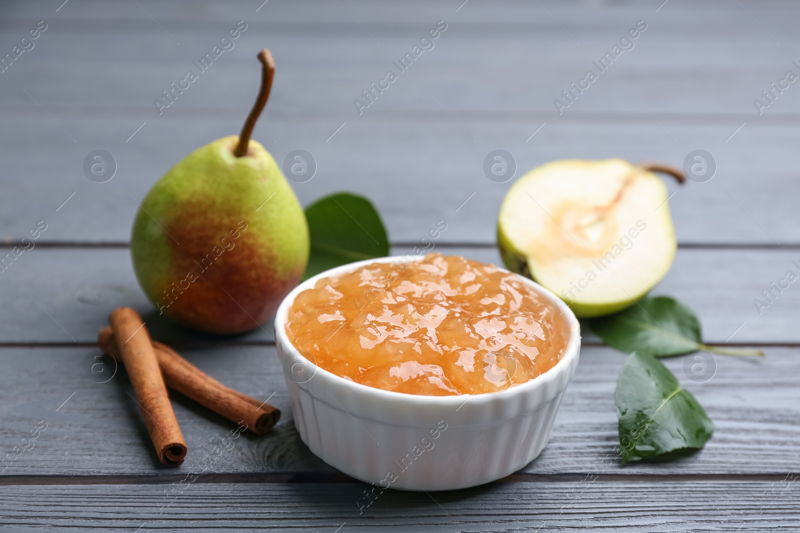 Photo of Delicious pear jam and fresh fruits on grey wooden table