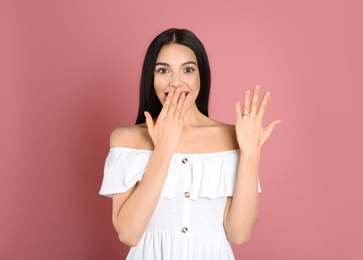 Photo of Emotional woman wearing beautiful engagement ring on pink background