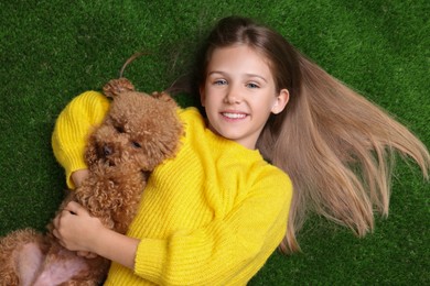 Photo of Little child with cute puppy on green grass, top view. Lovely pet