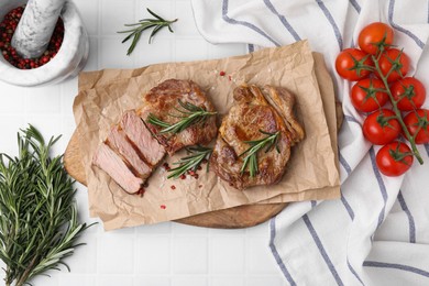 Photo of Delicious fried meat with rosemary served on white tiled table, flat lay