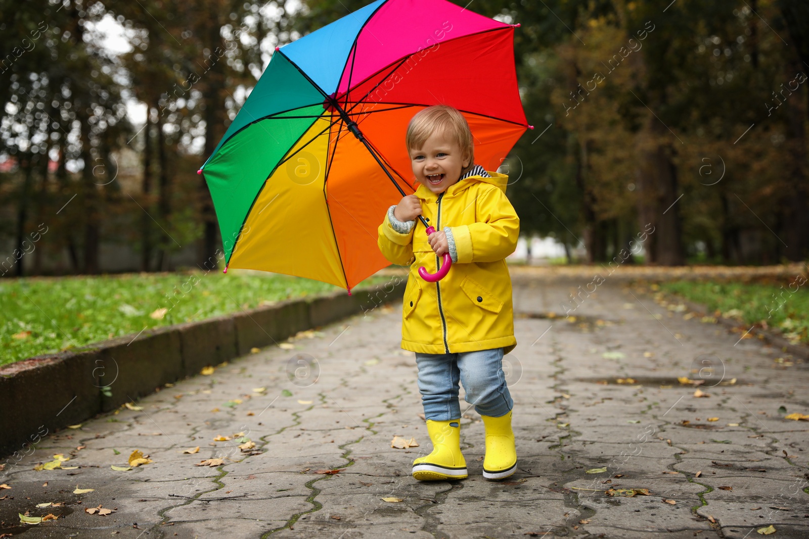 Photo of Little girl with colorful umbrella walking outdoors